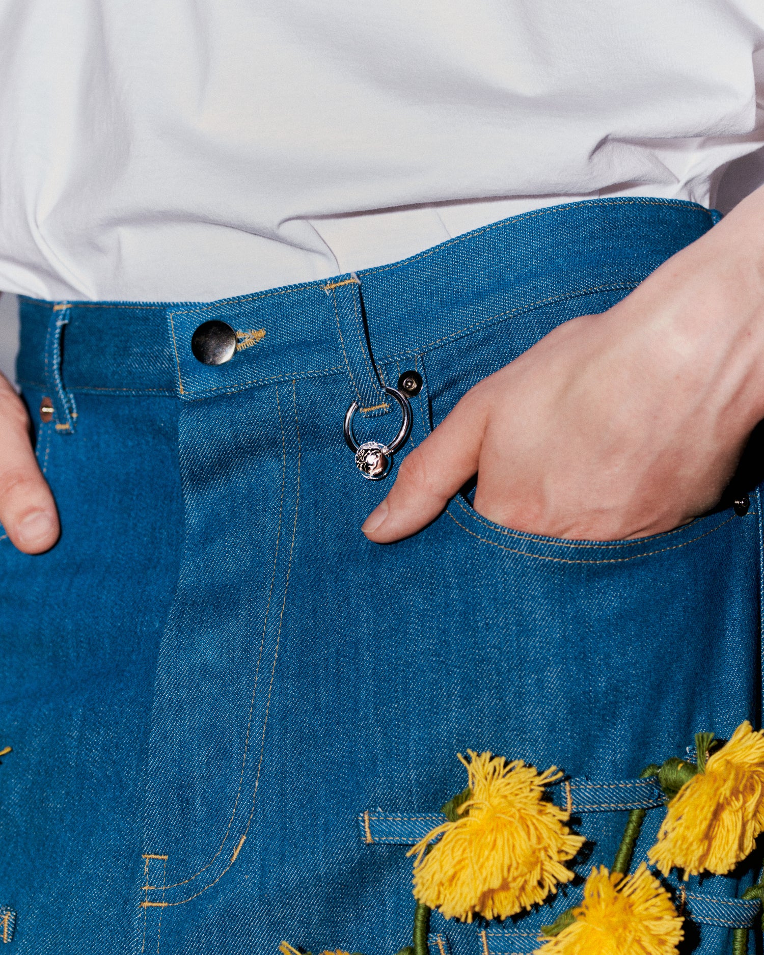 Hopeinen Rolf Ekroth x Kalevala Rakas-koru farkkujen vyölenkissä.